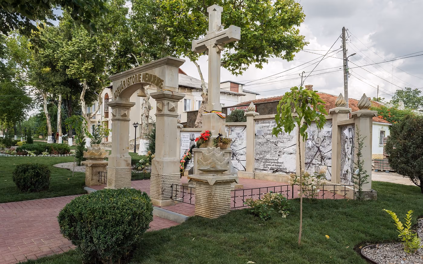 Monument din piatră deschisă într-un parc din Orhei: o arcadă cu inscripția „ADEVĂR ISTORIE NEMURIRE”, o cruce înaltă la mijloc și panouri cu fotografii și texte despre deportările din anii 1940–1941 și 1949, cu flori la baza crucii.